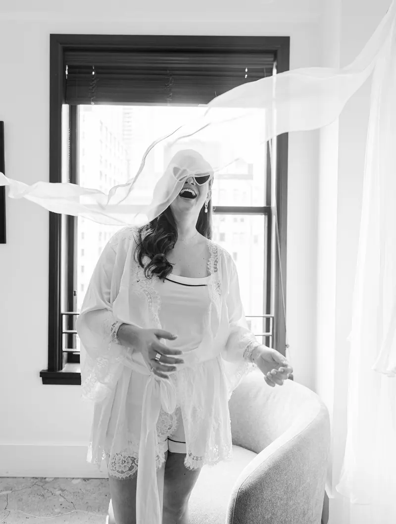 A bride laughing as her veil blows across her face.